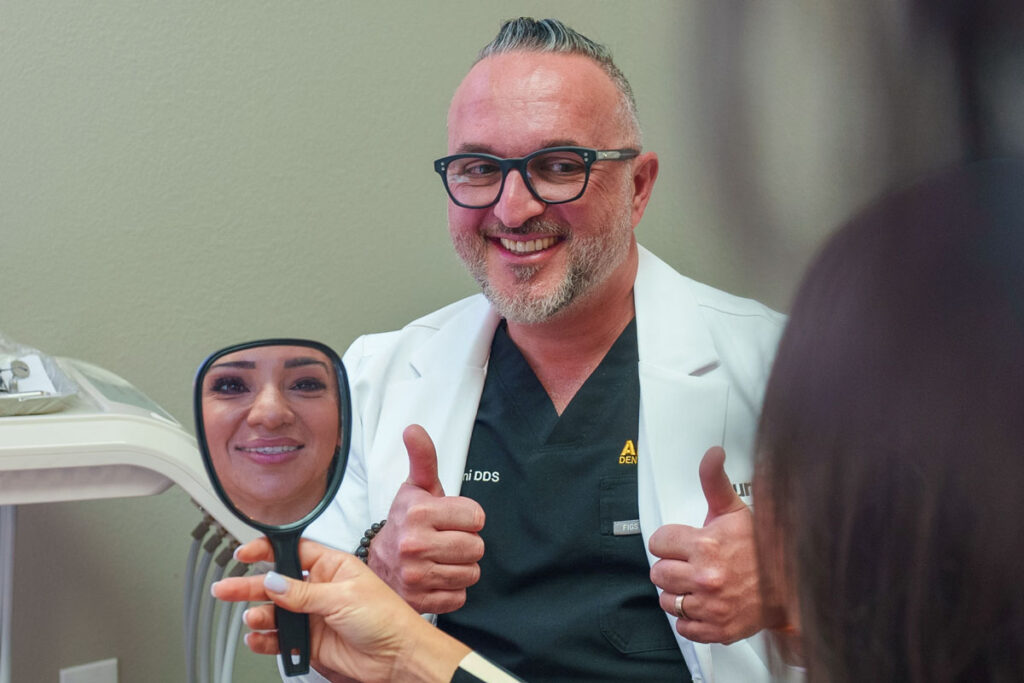 Dr. Baha Duraini with a smiling patient who is looking at her new smile in a hand mirror